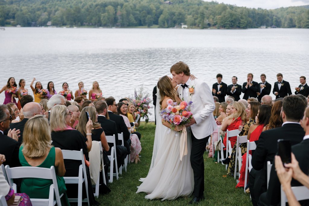 The bride and groom kiss before family and friends with views of Lake Toxaway.