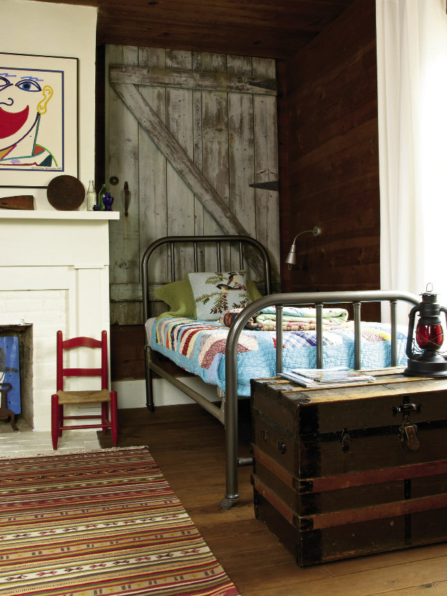 doors from a nearby cabin add a rustic touch above a pair of refinished iron beds dressed with cheery, colorful quilts.
