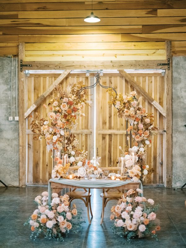 Graceful blush florals adorn and envelop the sweetheart table at the reception.