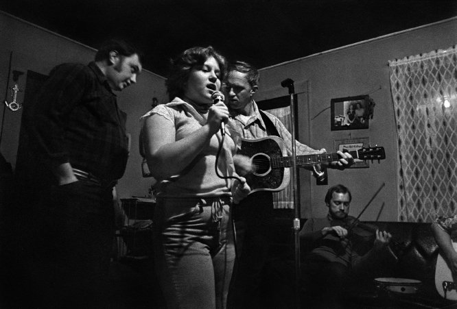 Rhonda Chandler singing with her uncle, Joe Chandler, and her father, Charles Chandler, at Dellie’s House, Sodom (1978) House singings have been common events in Madison County throughout much of its history and continue to this day. Rhonda’s  grandmother was noted ballad singer Inez Chandler, although Rhonda and her family sang more bluegrass and gospel.