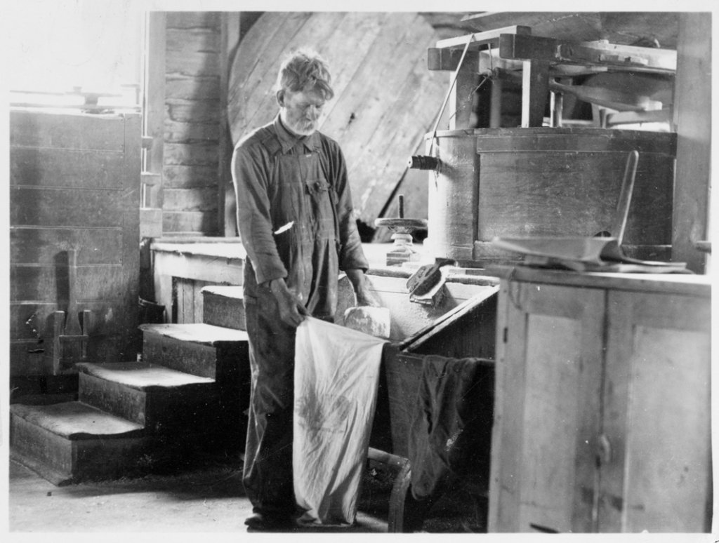 This photo, taken not long after the creation of Great Smoky Mountains National Park in 1934, shows a miller bagging cornmeal at Mingus Mill.