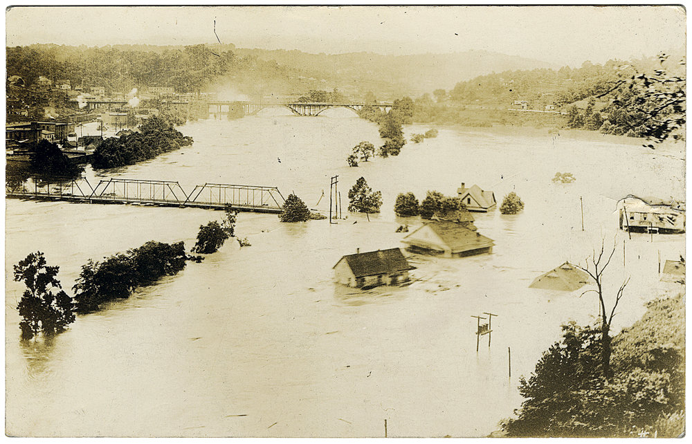 Smith’s Bridge, a steel structure that spanned the French Broad River between Asheville and West Asheville, in the midst of the flood, with portions already gone. Within a day of this photo, the remaining parts of the bridge were swept away as well.