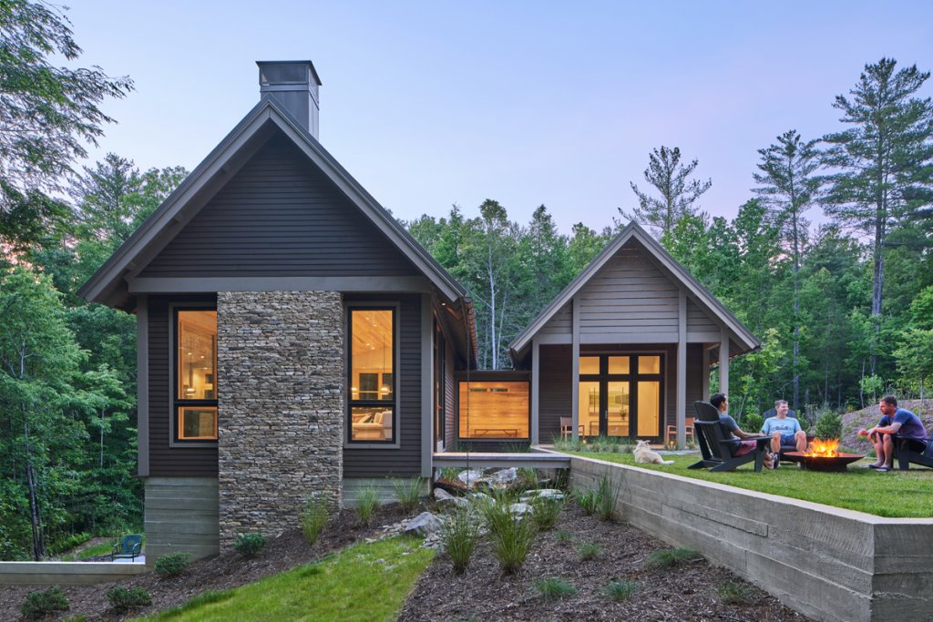 Connected - This home&#039;s construction flows with its unique surroundings; a short bridge above a rocky nook connects the far side of the home to a grassy space with firepits and chairs. Stone features and earthy colors create a stronger connection with the landscape, and, in turn, complete the “timeless” look.