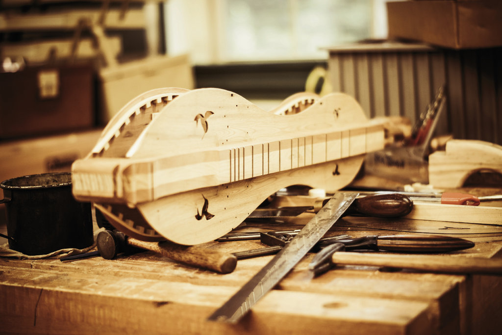 In the woodworking studio, a half-complete dulcimer sits on a workbench. The instrument will be finished by the end of the week.