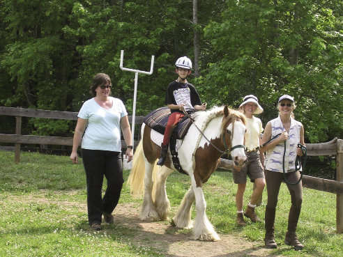 The intuitive nature of horses makes them gentle and understanding therapy companions. Above, TROT Administrative Director Robbie Hambright guides her horse, Jesse, with Austin Jackson in the saddle. The program relies on volunteers such as Diane Prewitt and Mary Smith, walking alongside.