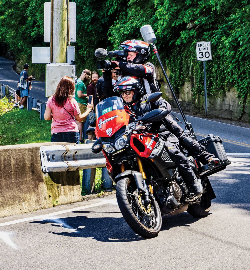 Dean Lyons piloting a cameraman in a bicycle race