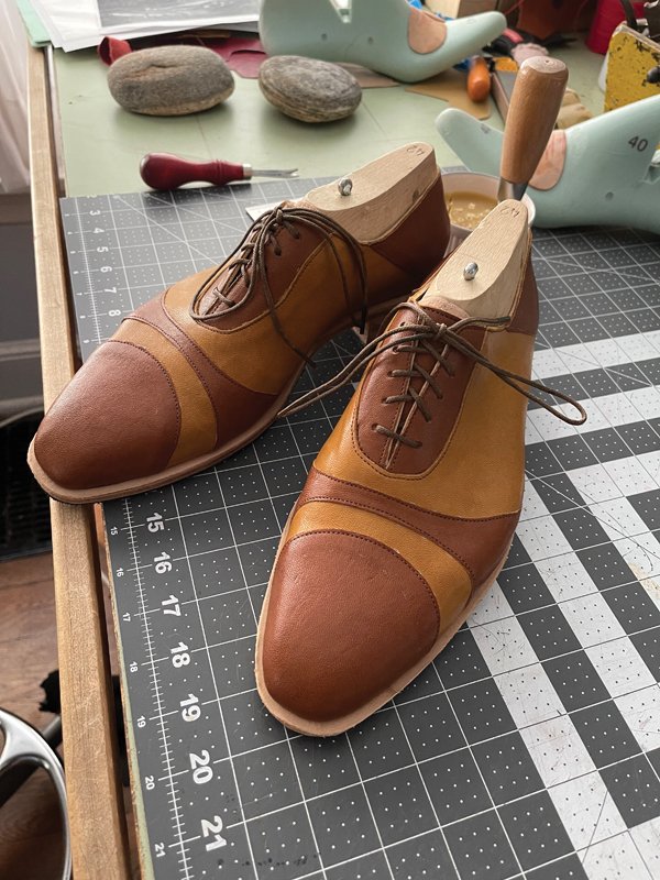 These two-toned lace-ups sit in wooden lasts that model the foot’s shape.