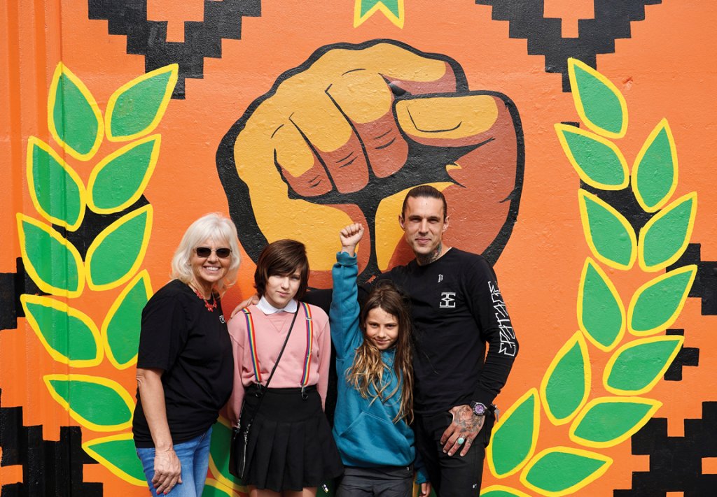 Brenda, Nex, Ezekiel, and Jared Wheatley in front of the mural they designed as a family. The raised fist, a global symbol of fighting oppression, is at 46 Aston Street.