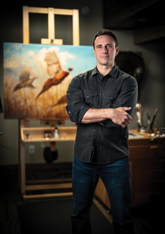 Ryan Kirby’s wildlife paintings earned him the title “Artist of the Year” at the Southeastern Wildlife Expo. Here, Kirby stands in front of his featured painting, The Departure.