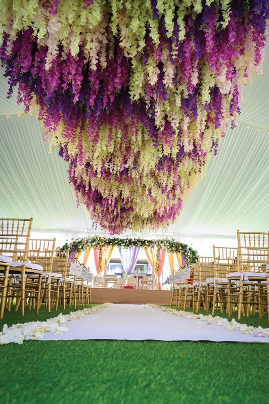Florals drip from the tented ceremony site to welcome the bride and groom down the aisle