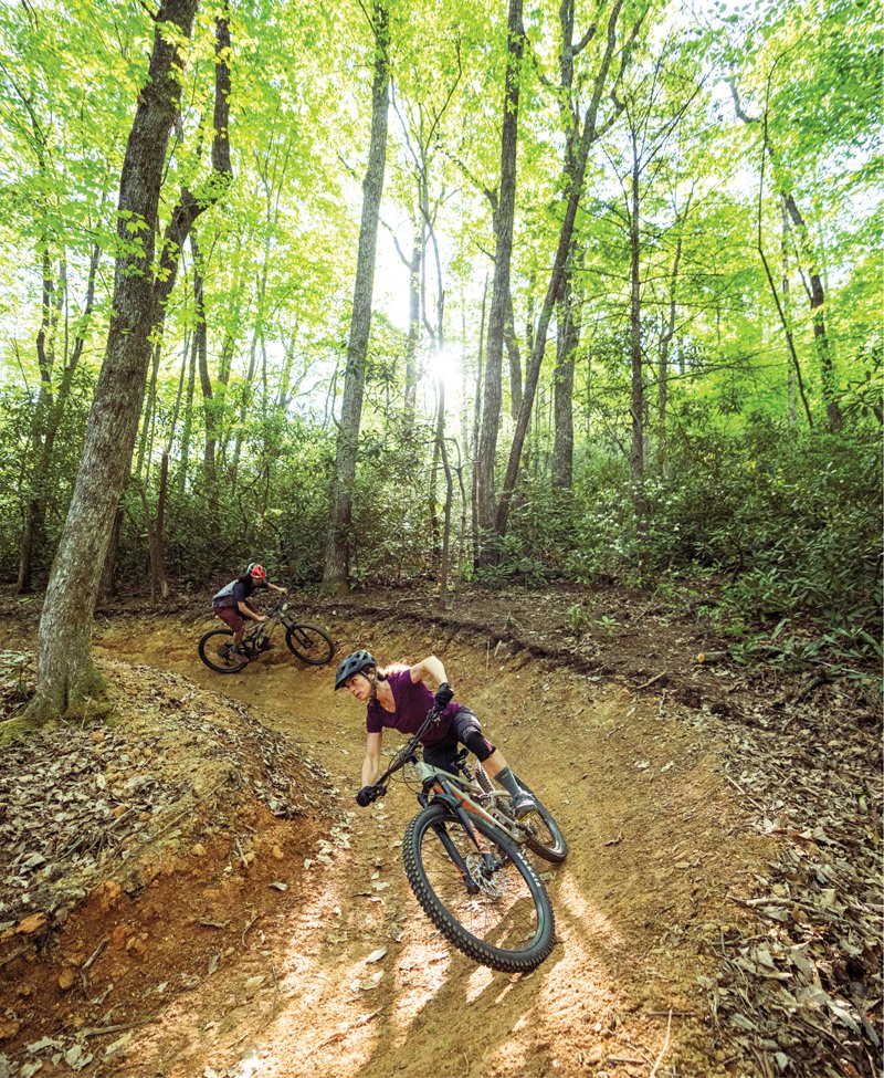 Two cyclists curve down the trail, wheels spinning over the popular dirt path in Old Fort.