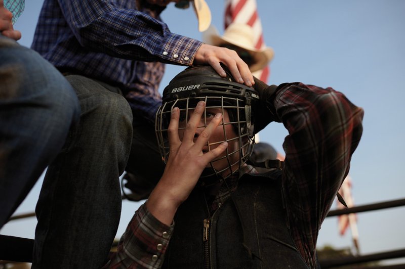 A friend helps secure a rider’s helmet.