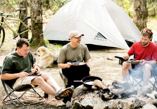 Ben Butler, Tom Gallo, and Jeff Dingus swap cycling tales over breakfast calzones and blue flannel hash at the campsite deep in Pisgah National Forest, which is known for its challenging bike trails.