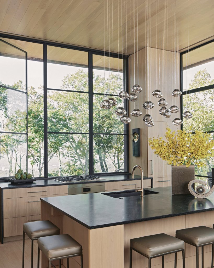 GET COOKING - The pendant over the kitchen island reflects the Milkey’s passion for glass art. Walls lined with opening windows preserve the connection to the land and mountainscapes of the Blue Ridge.