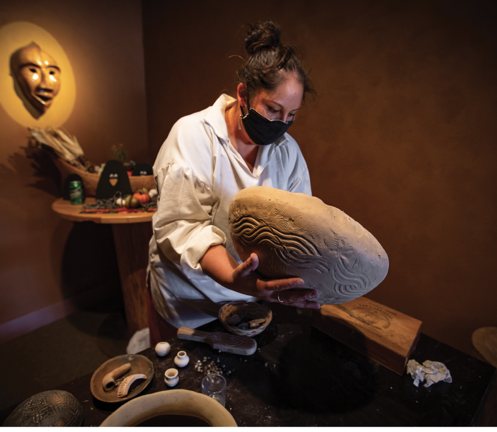 By using a pottery stamp, Eastern Cherokee potter Sarah Thompson creates a unique circular pattern across one-of-a-kind pottery. Here, Thompson is working in the Museum of the Cherokee Indian. The museum&#039;s mission is &quot;to preserve and perpetuate the history, culture, and stories of the Cherokee people.&quot;