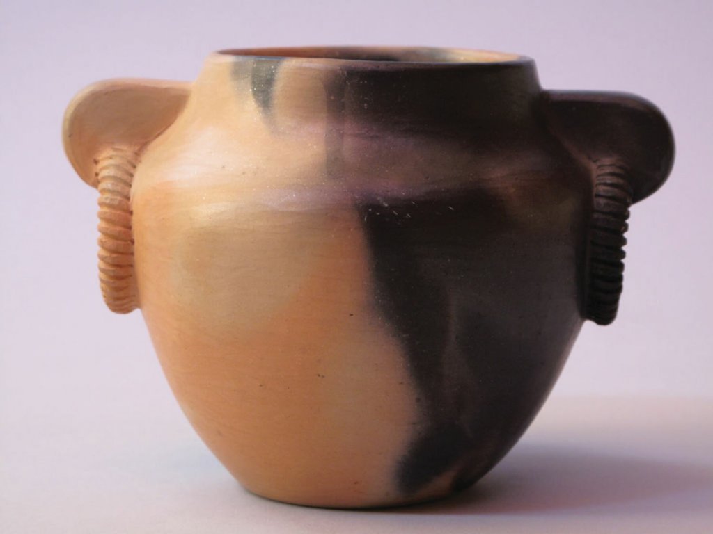 An earthenware vase by Cherokee potter Maude Welch, who was born in 1894. She achieved a dual color look by using different types of wood to fire on each side.