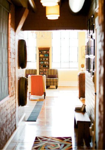 Scene Setter Enormous windows hint at the building’s manufacturing past and lure visitors into the sun-drenched living room. John’s vintage tobacco tins fill a custom shelf.
